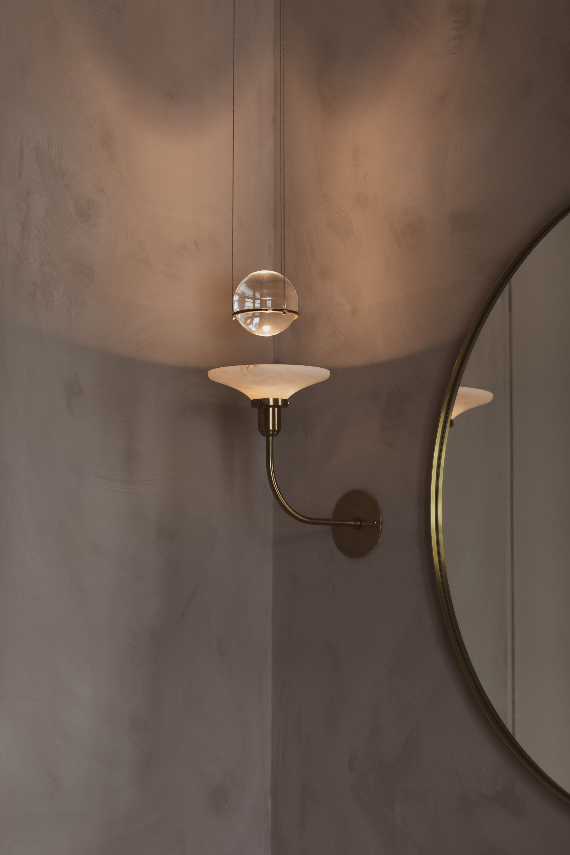 brass sconce against grey plaster walls