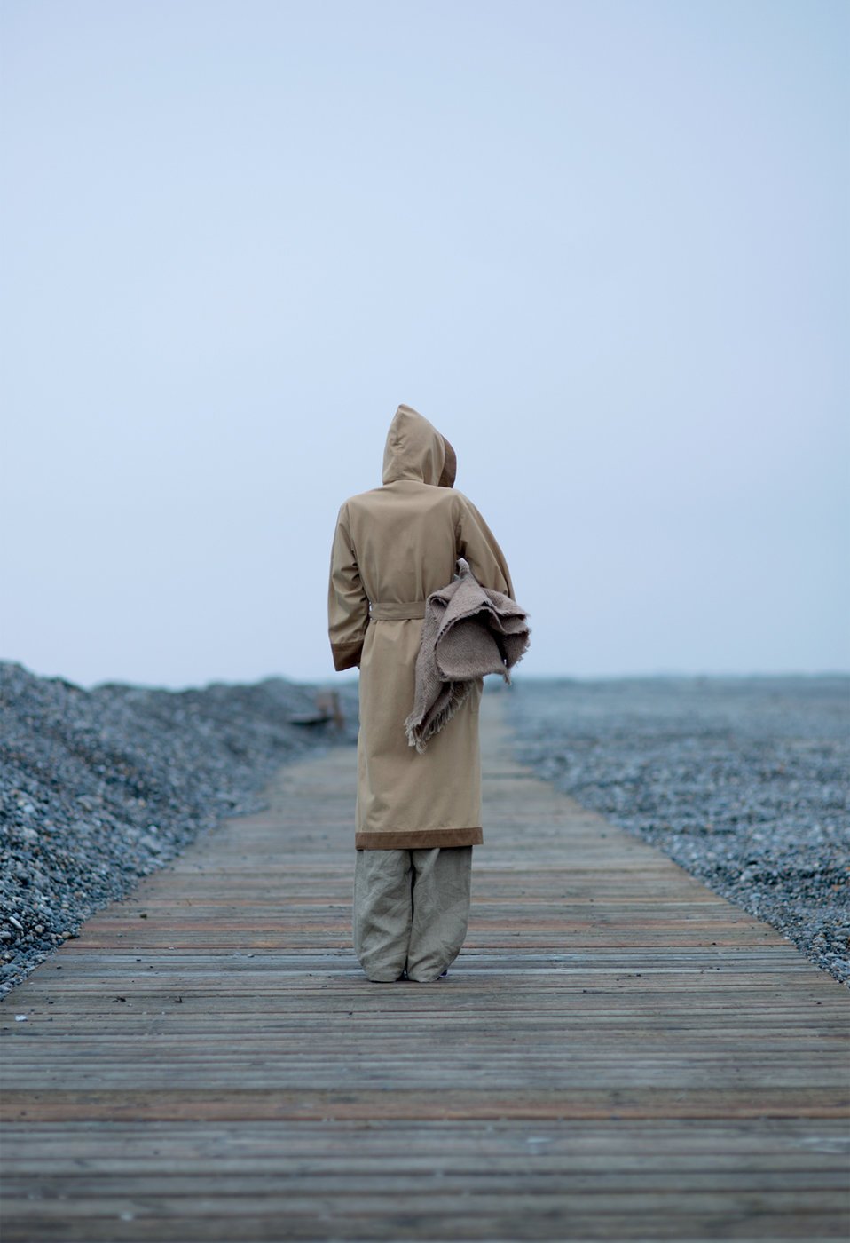 person stands on boardwalk turned away