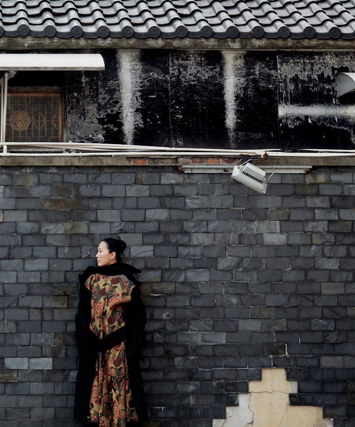 woman stands in front of brick wall