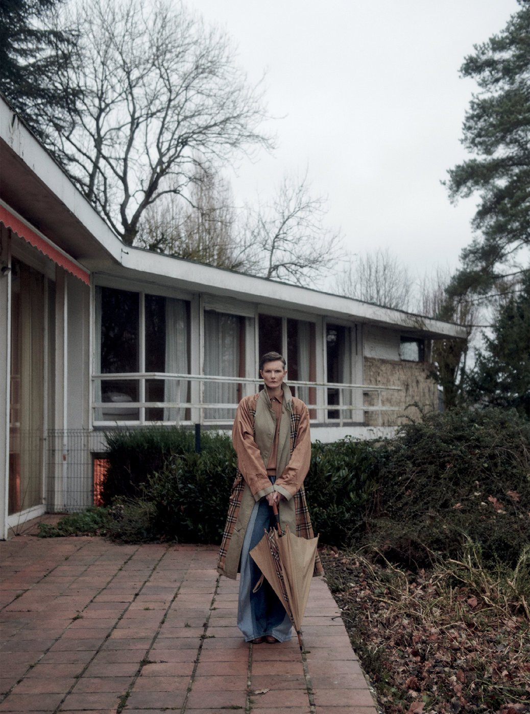 person stands in front of house holding umbrella