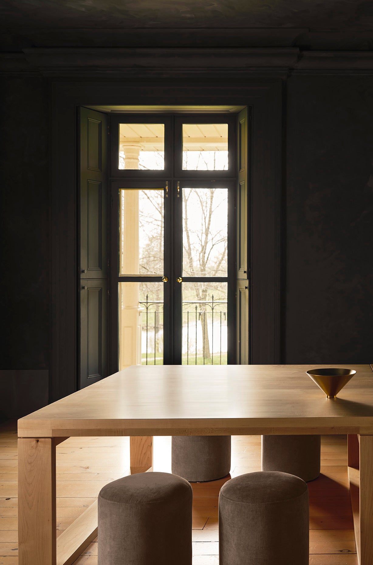 a warm wood table sits in front of french doors