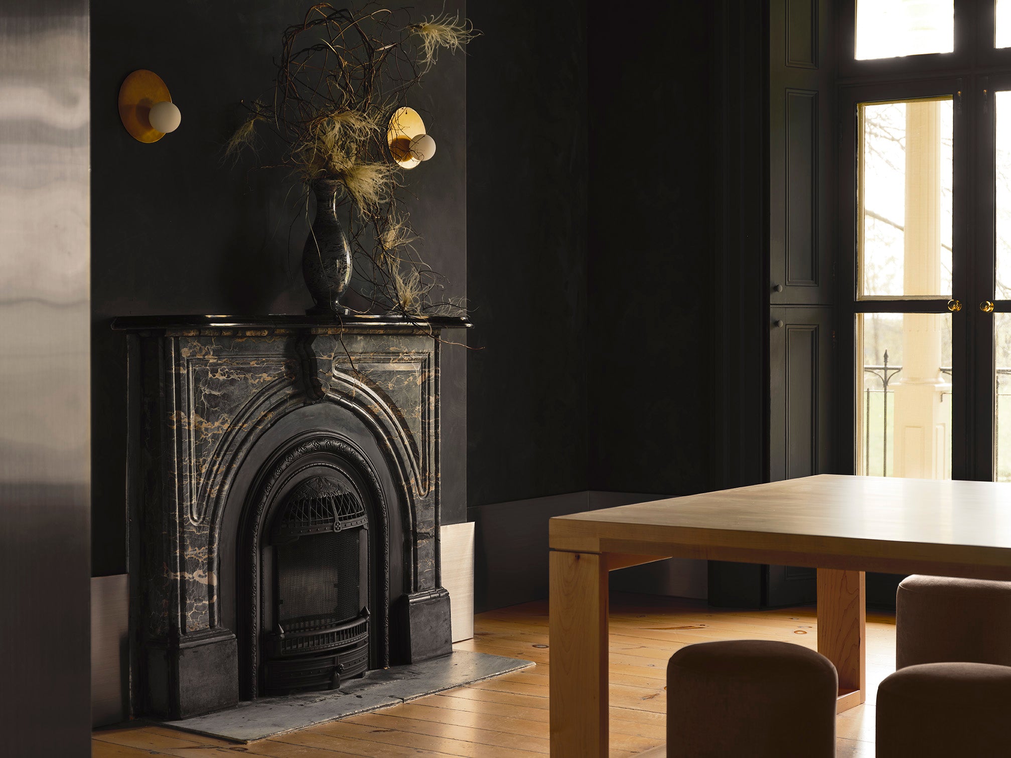 black marble fireplace sits in a large room with dark walls