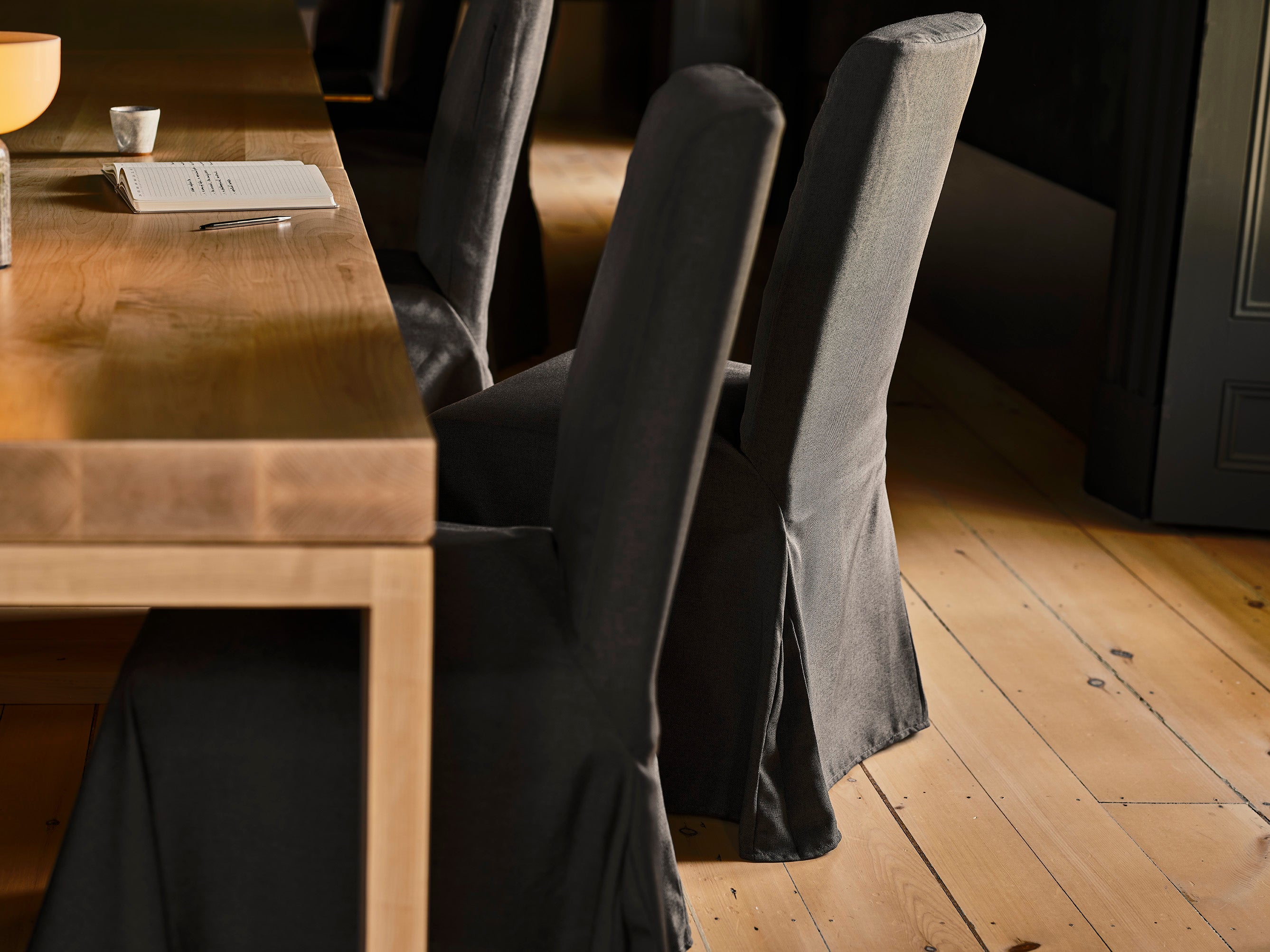 black linen covered chairs and a warm wood table