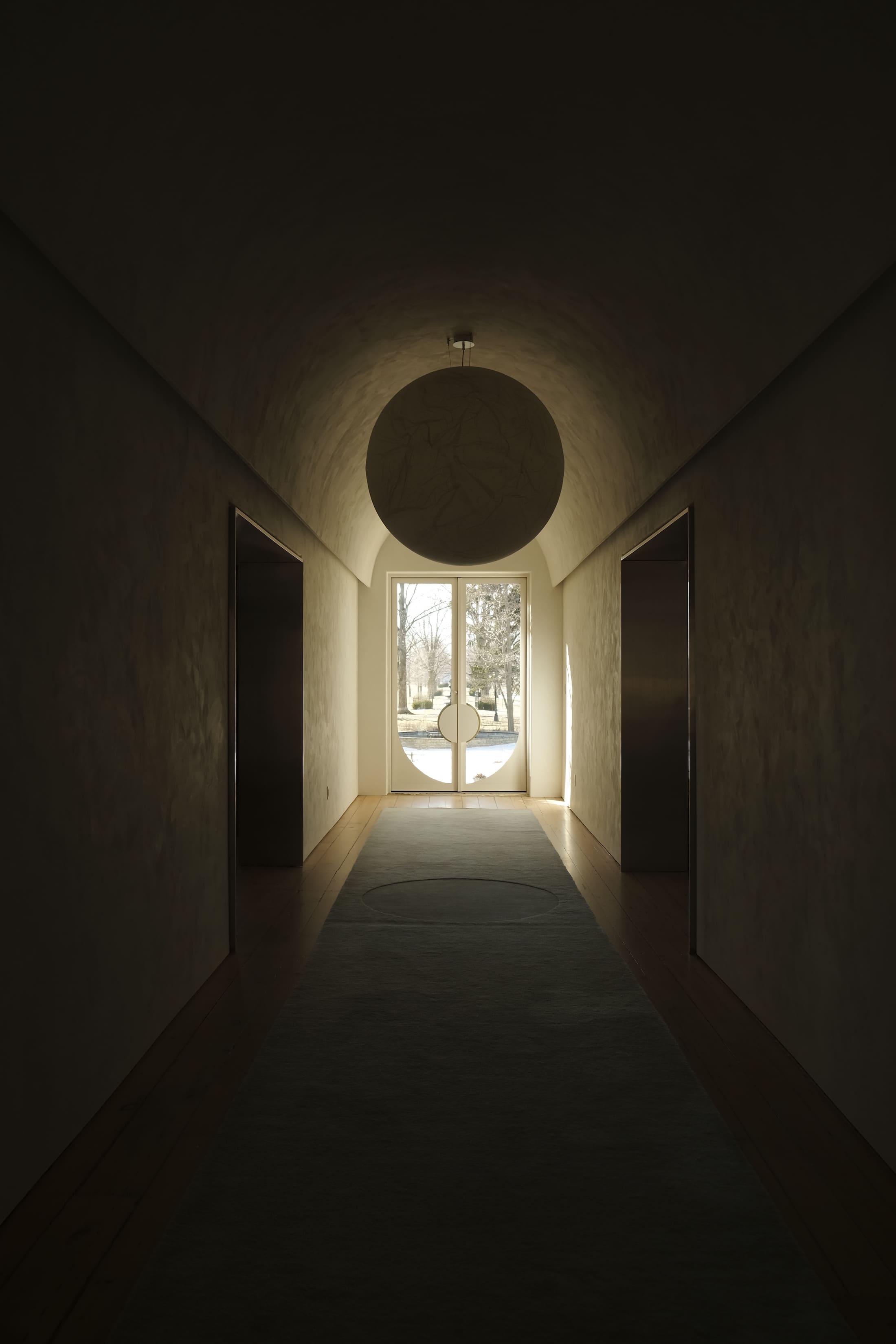 dramatic shadows fall in a long hallway, french doors overlook an iron fountain outside the house