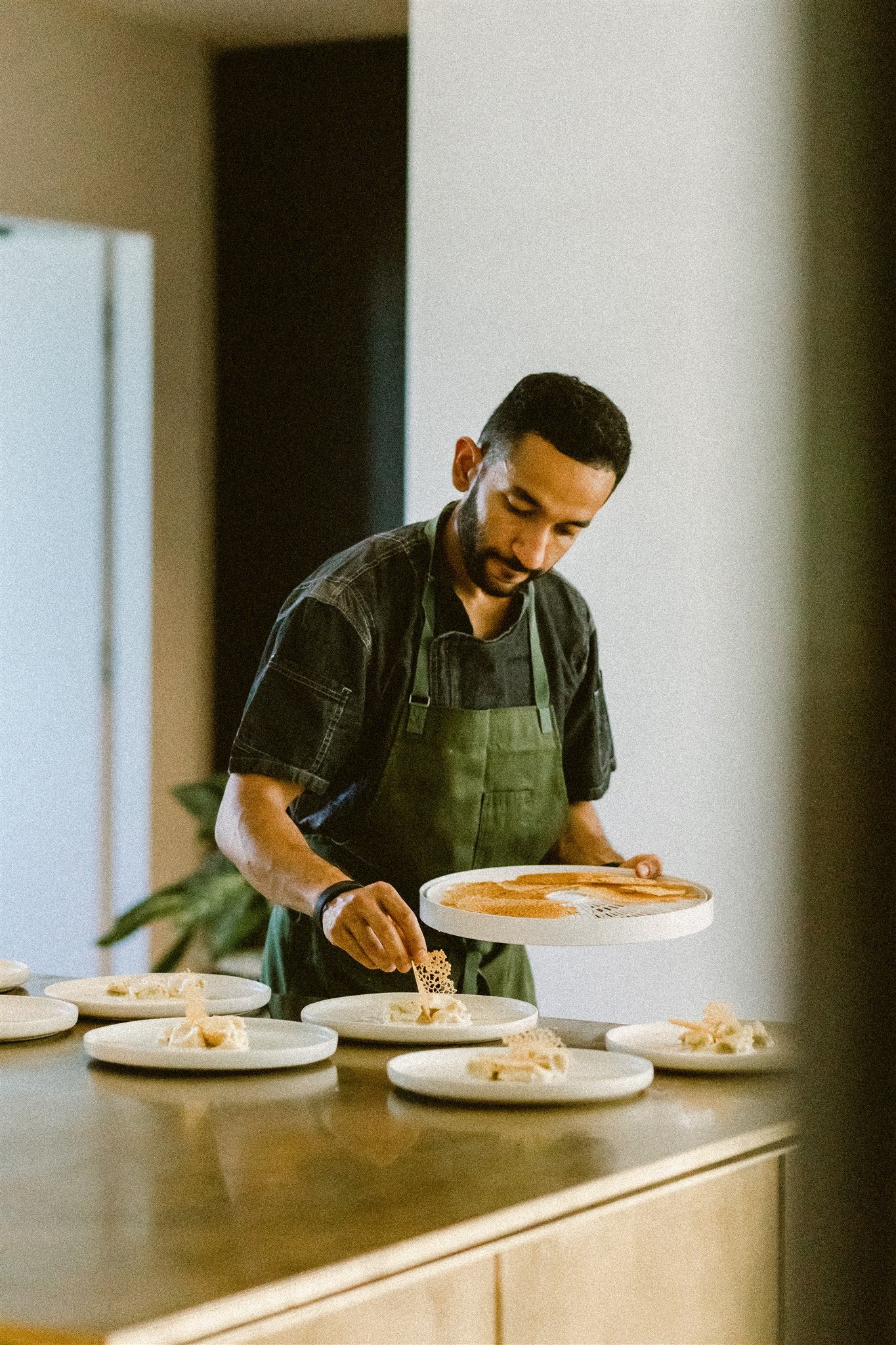 chef Aakash Dhall adds finishing touches to a series of plates