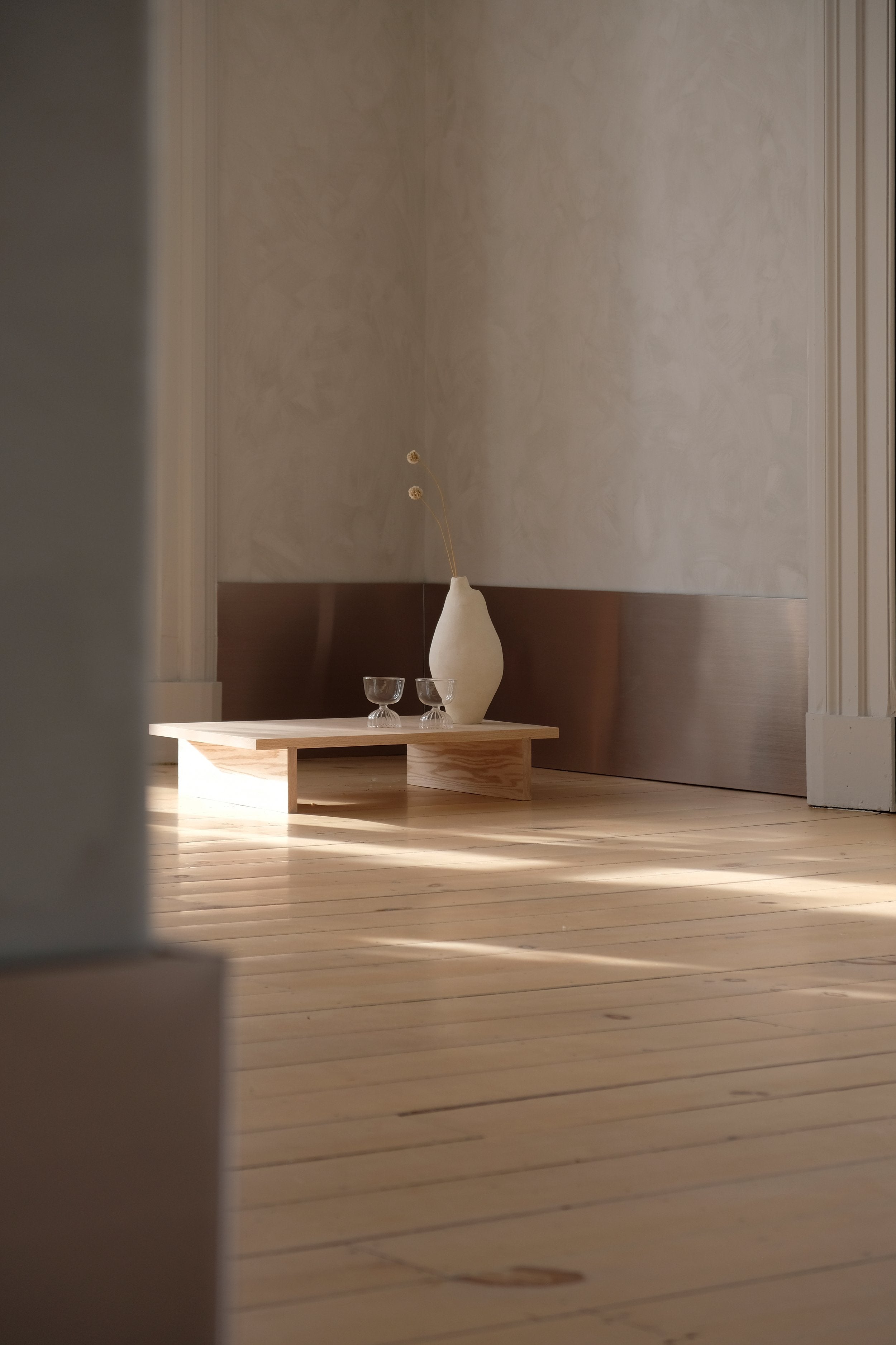 low wood table with large white vase on it