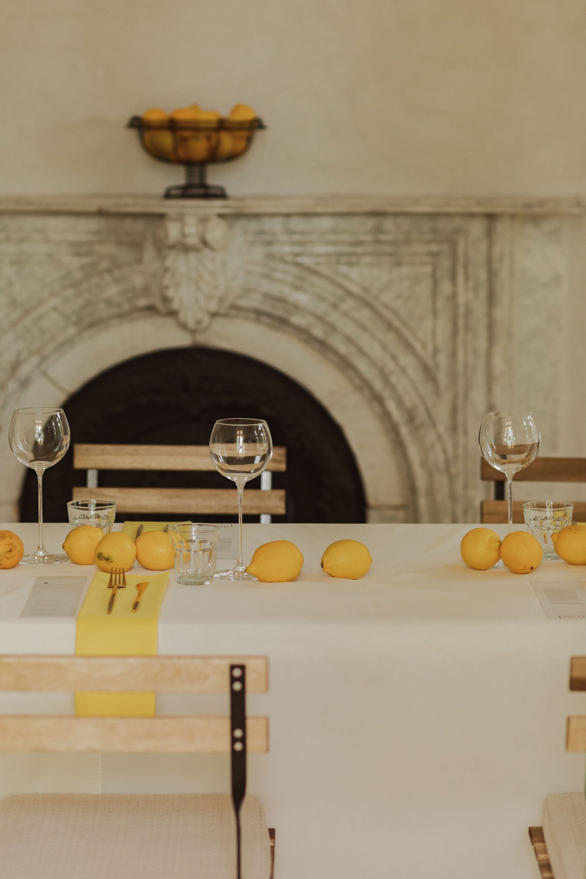 table set with lemons and tall wine glasses sits in front of white marble fireplace