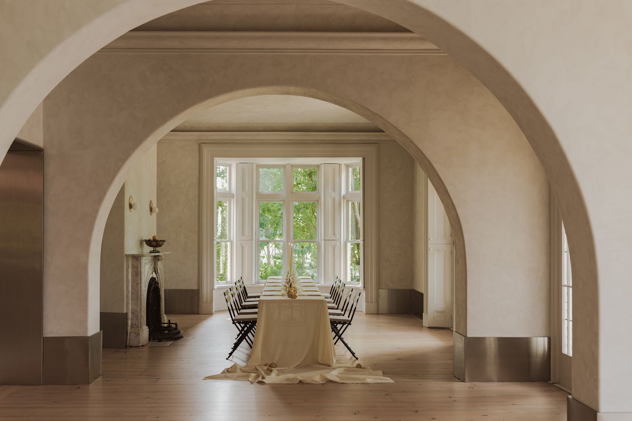 a long table inside a room with dramatic arches and a large bay window