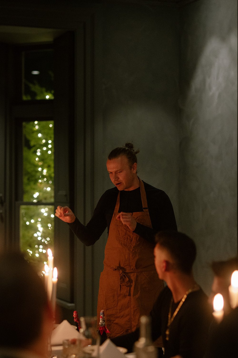 chef Chris Locke stands in front of candlelit table, explaining the menu to the guests