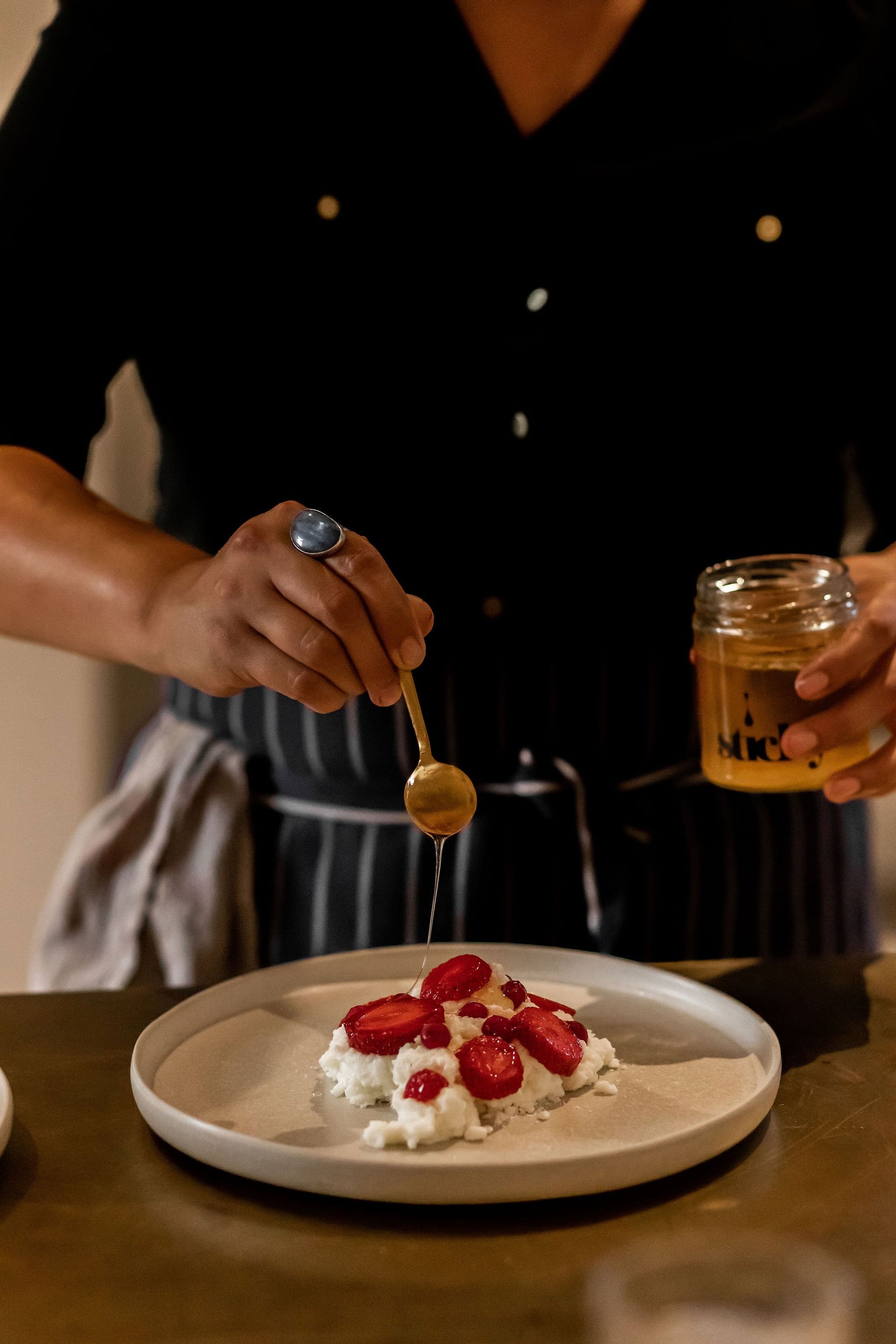 closeup of hand drizzling honey on to a dessert