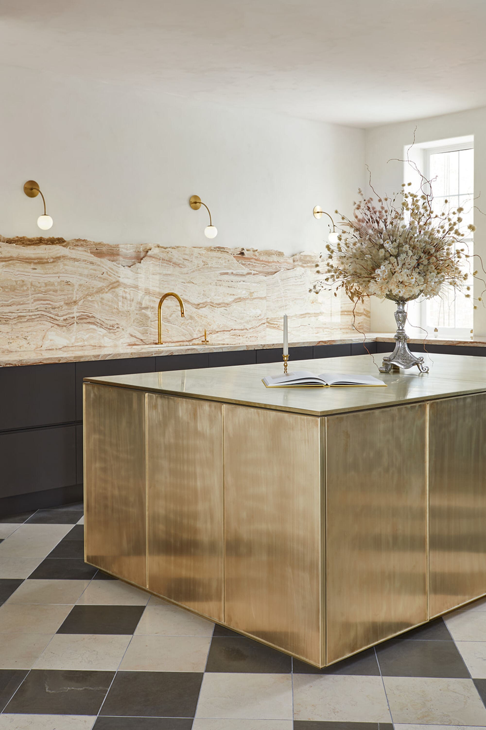 a large brass kitchen island in a kitchen with a dramatic marble backsplash