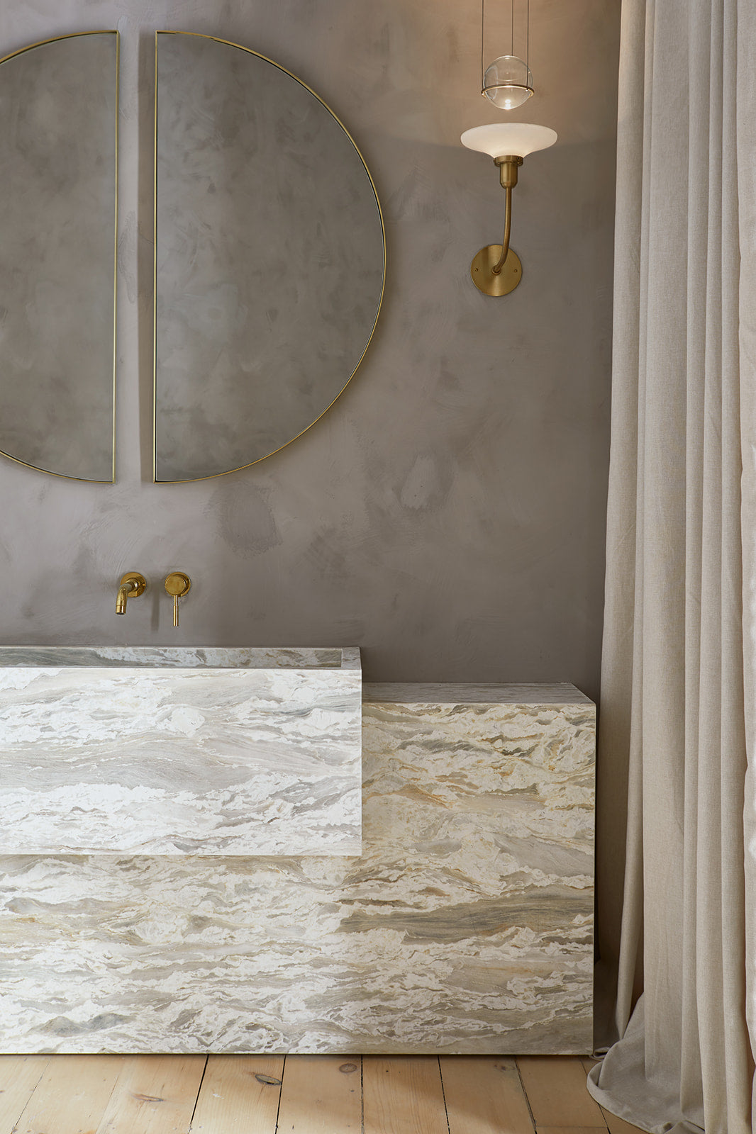 grey marble sink and vanity, large circular mirror with brass frame