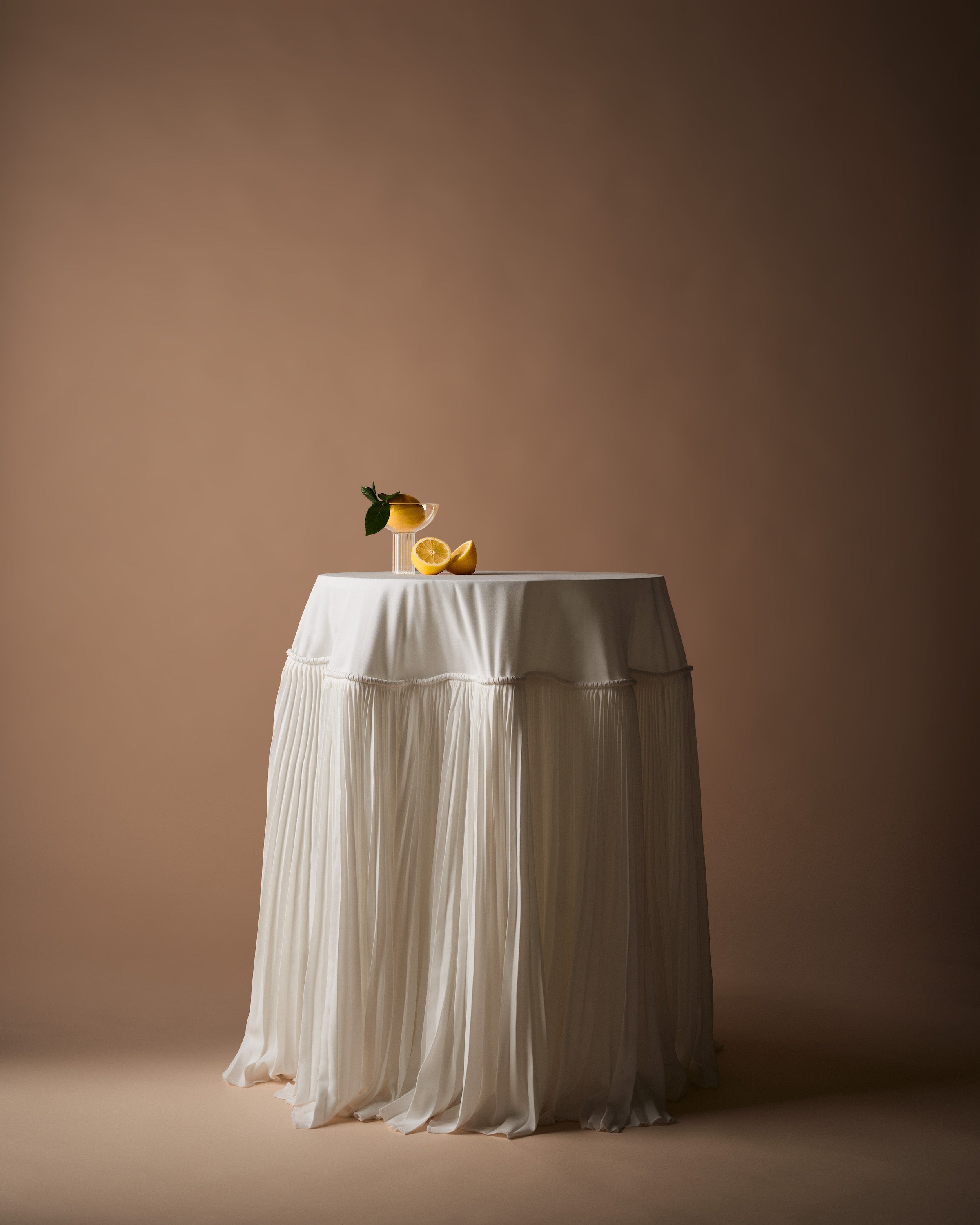 lemons sit on top of a table with a long flowing tablecloth