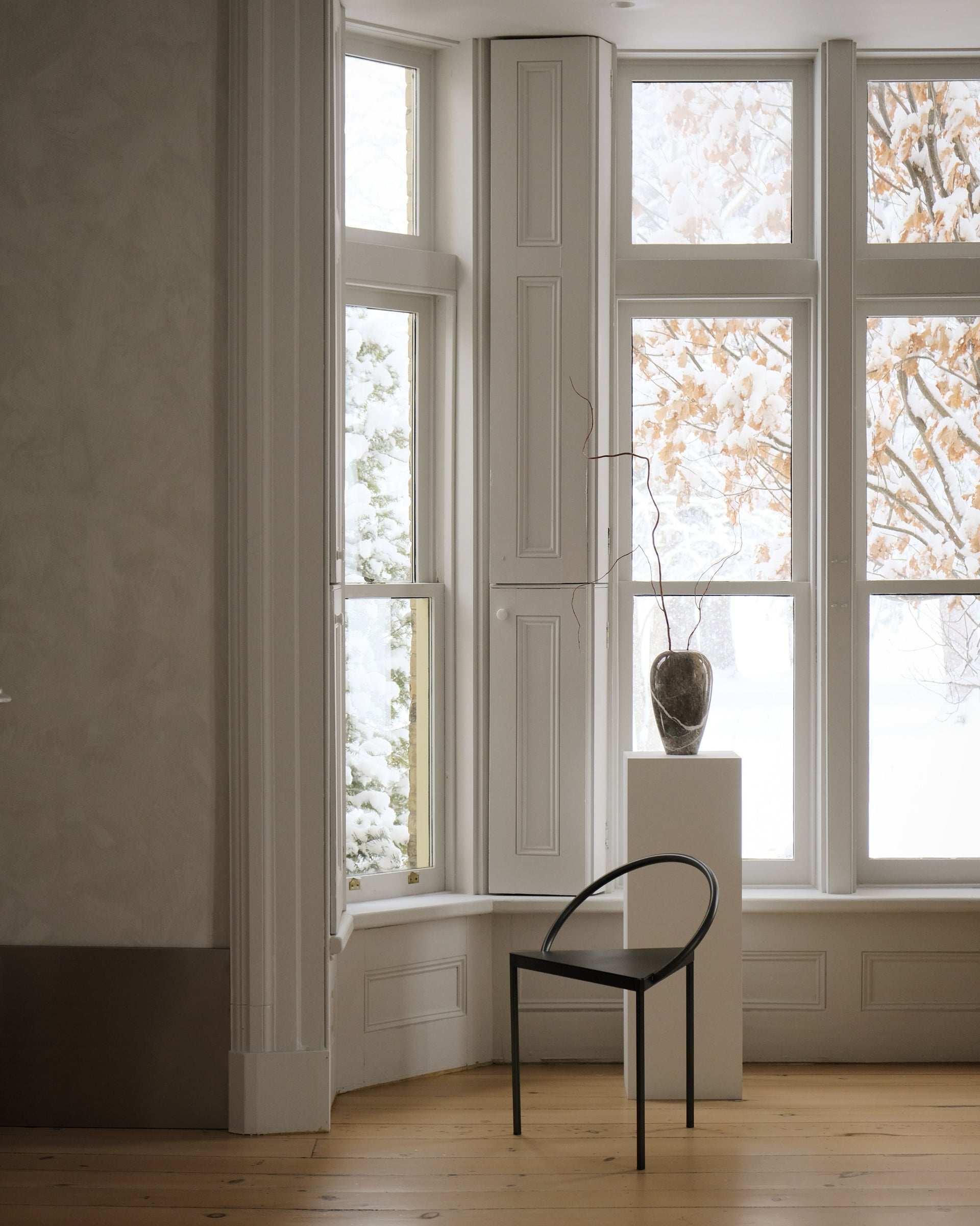 a black chair sits in front of a large bright window