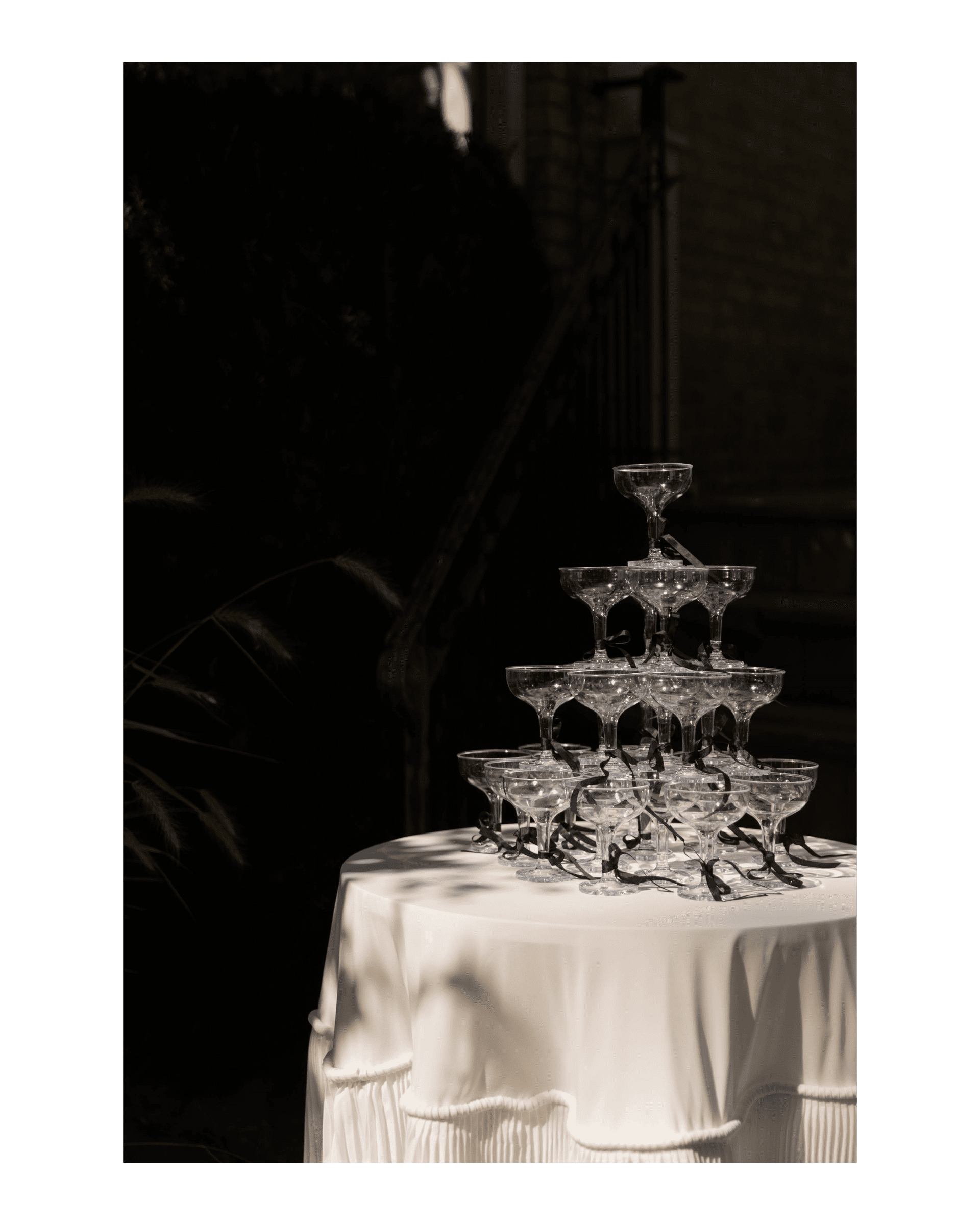 coupe glasses arranged in tower on top of a flowing white tablecloth