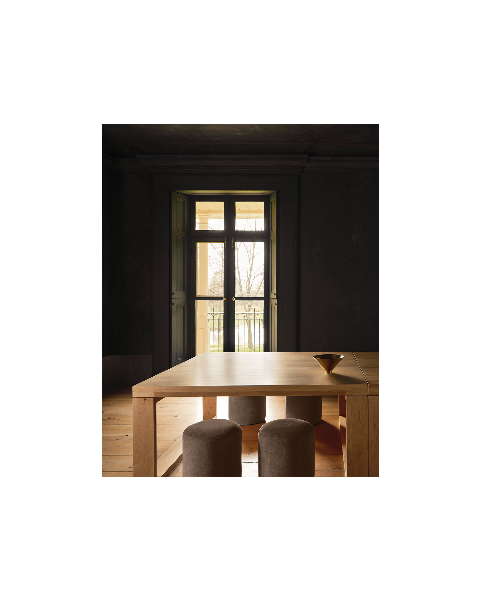 warm wood table in front of french doors, dark plaster walls