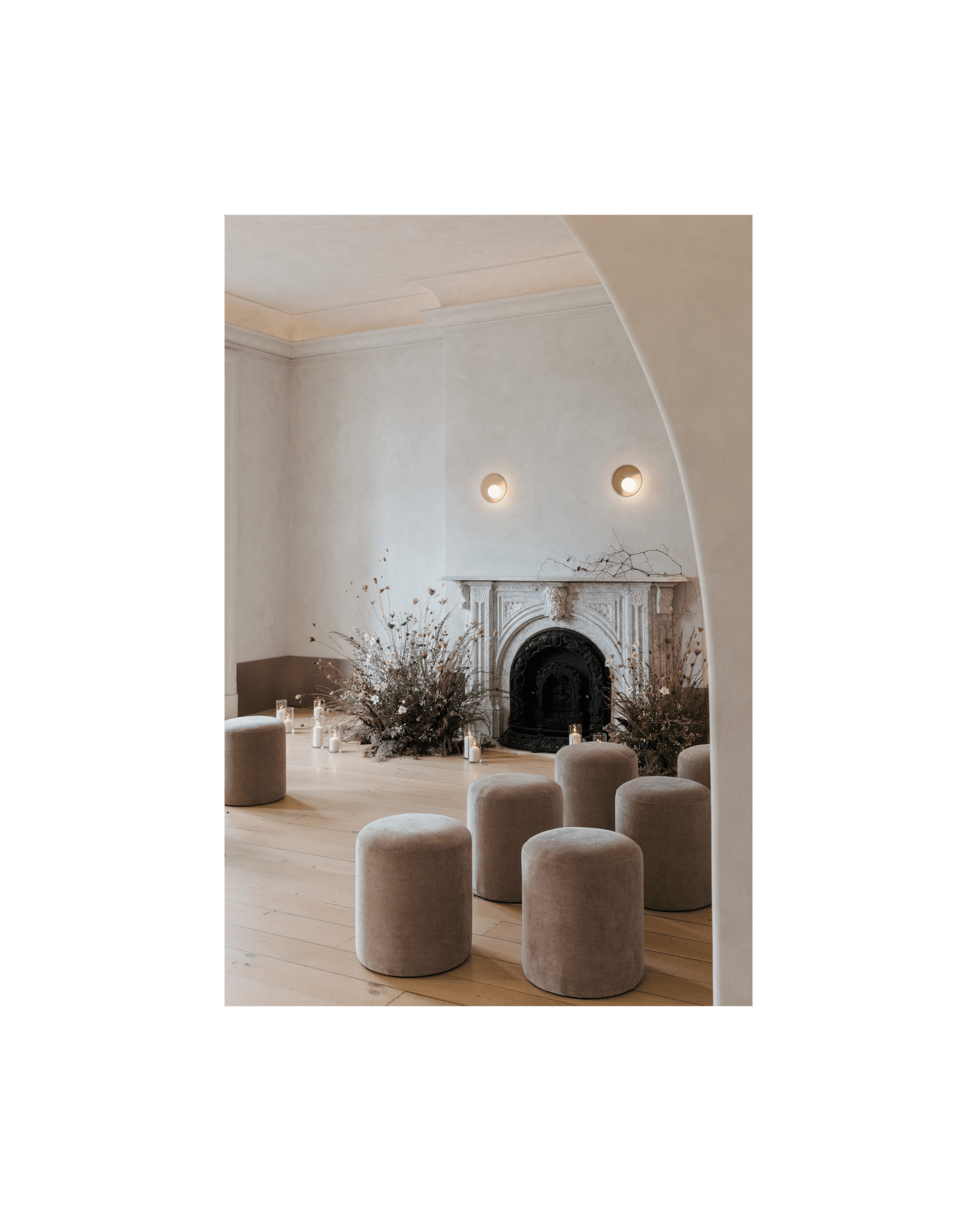 pink velvet stools arranged in front of white marble fireplace, florals sit on either side