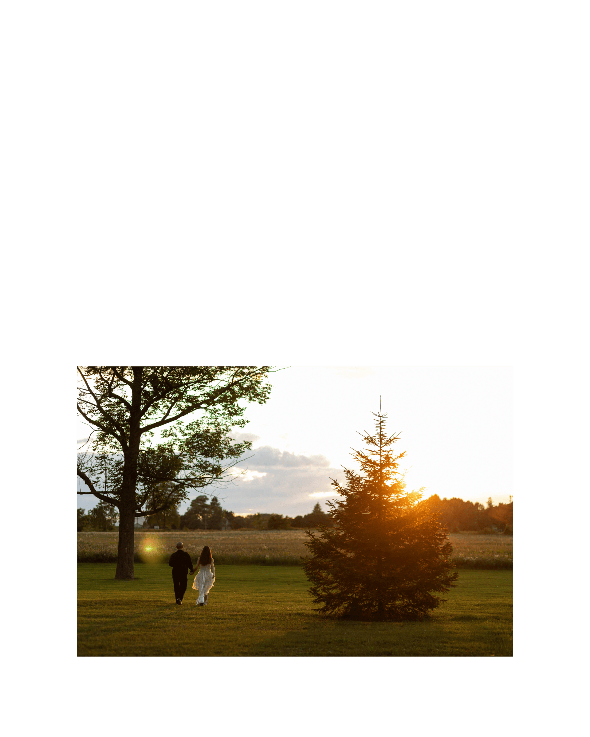 bride and groom holding hands walking into large field at sunset