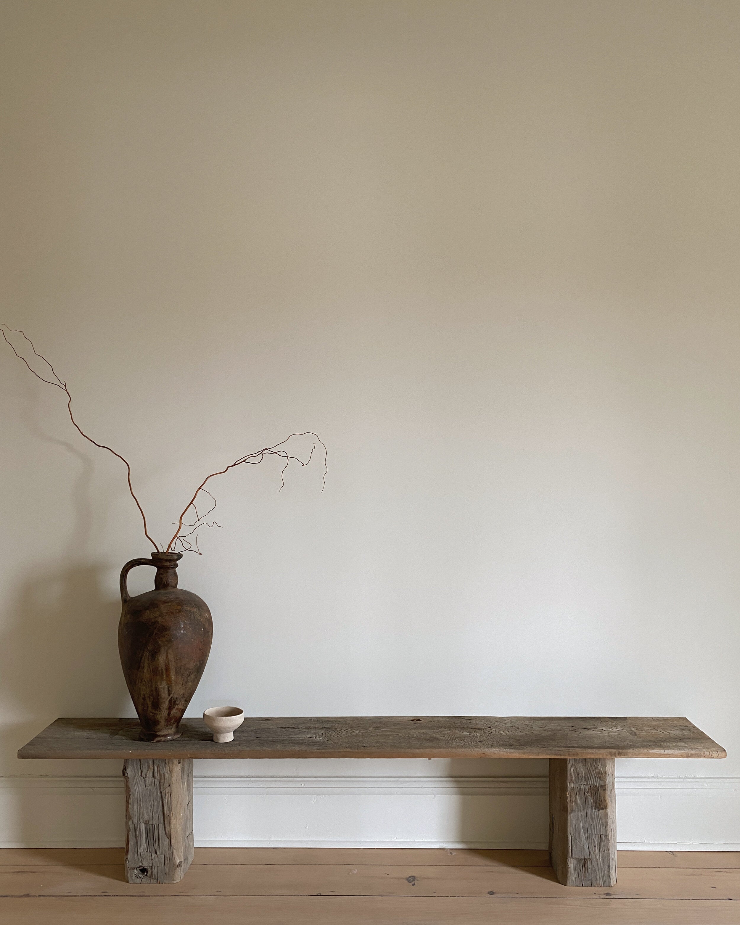 long wood bench with large black vase on it